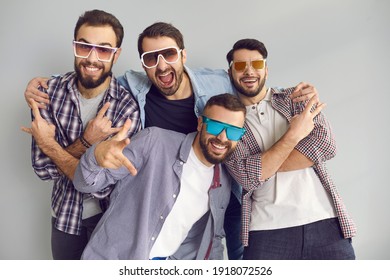 Happy young men in sunglasses smiling, looking at camera and posing for funny photo in studio with light gray background. Group of 4 best friends in cool glasses hanging out and having fun together - Shutterstock ID 1918072526