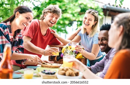 Happy young men and women toasting healthy orange fruit juice at farm house picnic - Life style concept with alternative friends having fun together on afternoon relax time - Bright vivid filter