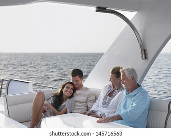 Happy young and middle aged couples relaxing on yacht