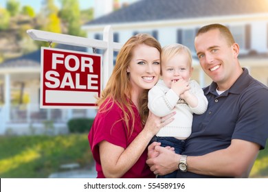 Happy Young Military Family In Front Of For Sale Real Estate Sign And New House.