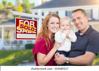 Happy Young Military Family in Front of Sold For Sale Real Estate Sign and New House.