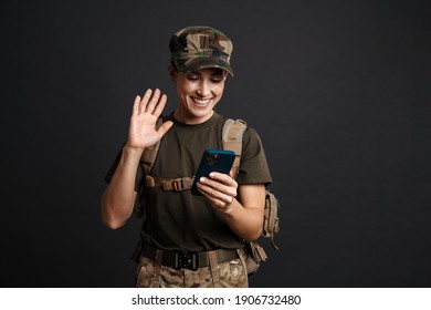 Happy Young Military Woman On A Video Call With Her Family Through Mobile Phone Isolated Over Black Background