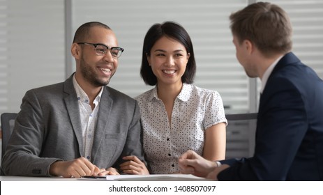 Happy Young Mixed Ethnicity Family Couple Customers Listening To Bank Manager Broker Insurer Consulting Clients Explaining Mortgage Investment Insurance Real Estate Deal Benefits At Business Meeting