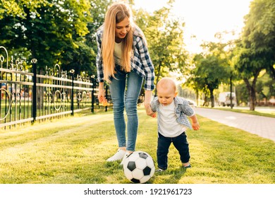 Happy Young Mom And Her Little Son Play Soccer Together Outdoors In The Park