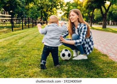 Happy Young Mom And Her Little Son Play Soccer Together Outdoors In The Park