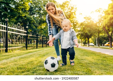 Happy Young Mom And Her Little Son Play Soccer Together Outdoors In The Park