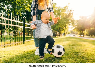 Happy Young Mom And Her Little Son Play Soccer Together Outdoors In The Park