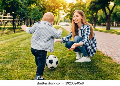 Happy Young Mom And Her Little Son Play Soccer Together Outdoors In The Park