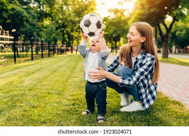 Happy Young Mom And Her Little Son Play Soccer Together Outdoors In The Park