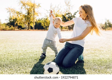 Happy Young Mom With Son Playing With Soccer Ball On Field, Outdoors