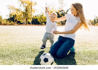 Happy Young Mom With Son Playing With Soccer Ball On Field, Outdoors