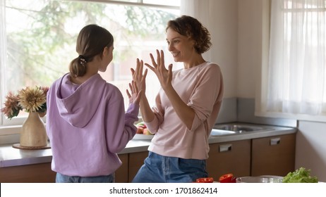 Happy Young Mom And Teenage Daughter Having Fun Dancing In Kitchen. Smiling Mommy Teaching Teen Kid Girl To Wash Showing Clean Hands Before Cooking Or Eating Enjoying Family Life Together At Home.