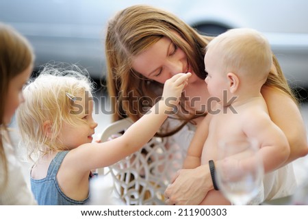Happy young mother with children in a outdoors cafe