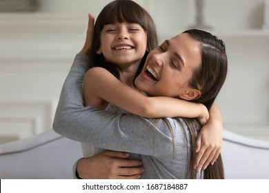 Happy Young Mother And Cute Little Preschooler Daughter Hug And Cuddle Showing Love And Care, Smiling Small Girl Child Embrace Overjoyed Mom Enjoy Family Time Weekend Together, Bonding Concept