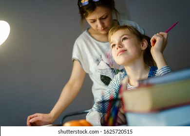 Happy Young Mother Helping Her Daughter While Studying At Home Getting Ready For School