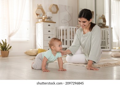 Happy young mother helping her cute baby to crawl on floor at home - Powered by Shutterstock