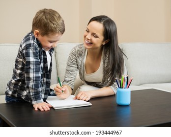 Happy young mother and her son drawing in home interior 