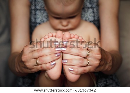Happy young mother holding little feet of her son