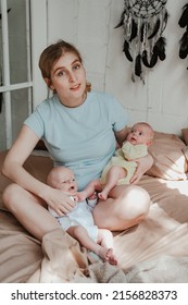 Happy Young Mother Holding Two Twin Babies In Bed At Home