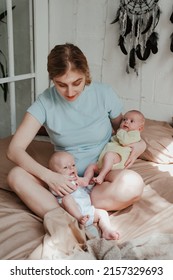 Happy Young Mother Holding Two Twin Babies In Bed At Home