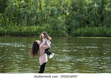 Happy young mother playing together with her adorable little daughter in beautiful scenic spring environment