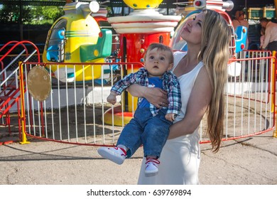 Happy young mother and son watching carousels in the amusement park - Shutterstock ID 639769894