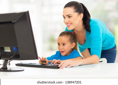 Happy Young Mother Teaching Daughter Computer At Home