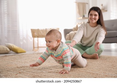 Happy young mother watching her cute baby crawl on floor at home - Powered by Shutterstock