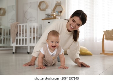 Happy young mother watching her cute baby crawl on floor at home