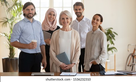 Happy Young Multicultural Office Team People And Middle Aged Old Company Ceo Leader Boss Stand Together Look At Camera, Smiling Confident Diverse Professional Employees Staff Group Corporate Portrait