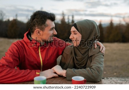 A happy young Muslim couple enjoys relaxing while drinking a cup of coffee in nature on holiday. 