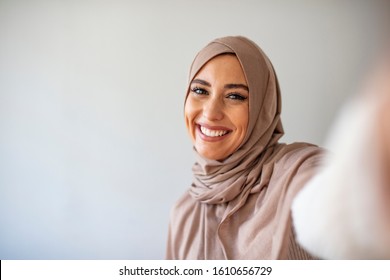 Happy Young Muslim Woman Take Self Portrait With Handphone At Home. Happy Arab Woman In Hijab With Mobile Phone Making Selfie. Portrait Of Smiling Girl, Posing.