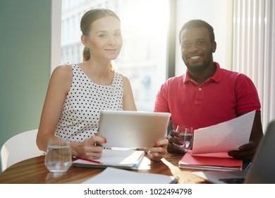Happy young office staff in casualwear looking at camera with smiles while working over project - Shutterstock ID 1022494798