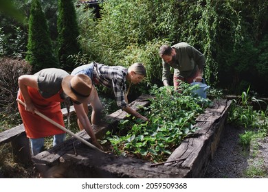 Happy Young And Old Farmers Working With Garden Tools Outdoors At Community Farm.