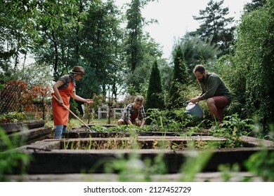 Happy Young And Old Farmers Working With Garden Tools Outdoors At Community Farm.