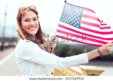 Happy young patriot urban woman with toothy smile stretching star spangled banner