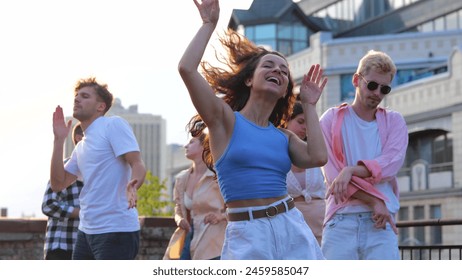 Happy young people dance on a roof having fun together. Caucasian beautiful brunette carefree woman jumping dancing in good mood at party. Summer. Urban life. Slow motion - Powered by Shutterstock