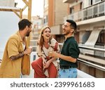 Happy young people having fun during a rooftop party during a summer holiday, standing on the rooftop terrace talking, eating and drinking, love, romance, relationship, flirting and youth culture 