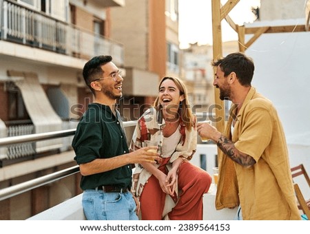 Happy young people having fun during a rooftop party during a summer holiday, standing on the rooftop terrace talking, eating and drinking, love, romance, relationship, flirting and youth culture 