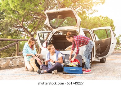 Happy Young People Pack Their Suitcase For A Beautiful Roadtrip Holiday Adventure With The Car. Best Friends Chill And Having Fun Making Jokes About The Travel Trip. Concept Af Adventure And Travel.