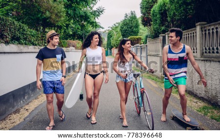 Happy young people walking along road in summer day