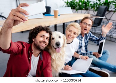 happy young people taking selfie with dog in office  - Powered by Shutterstock