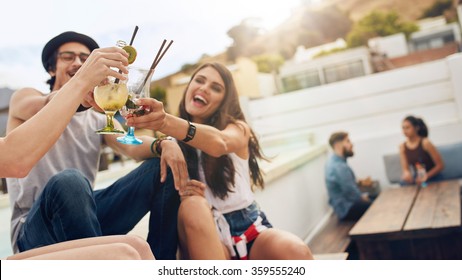 Happy Young People Toasting Cocktails At A Rooftop Party. Young Friends Hanging Out And Enjoying Drinks.