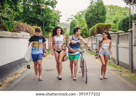 Happy young people walking along road in summer day