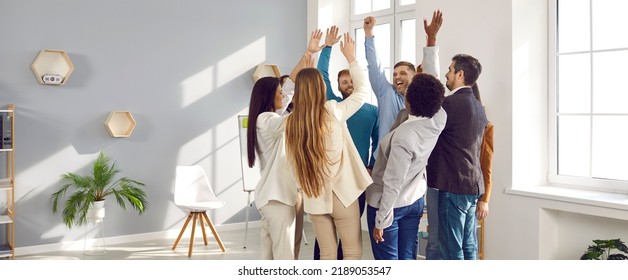 Happy young peoples stand in circle raise their hands up with smile during team building business events and creating friendly command located in spacious bright room. Corporate culture concept