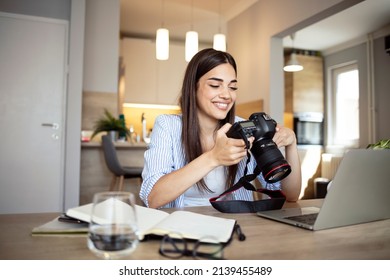 Happy young photographer holding a dslr camera in her home office. Female photographer smiling cheerfully while working at her desk. Creative female freelancer working on a new project. - Shutterstock ID 2139455489