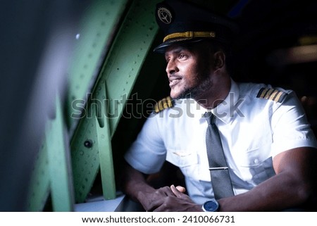 happy young pilot in professional uniform at airport. Male pilot sitting in airplane cockpit