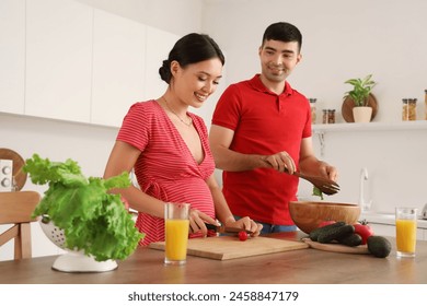 Happy young pregnant couple cooking in kitchen - Powered by Shutterstock