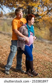 Happy and young pregnant couple hugging in nature - Shutterstock ID 253381897