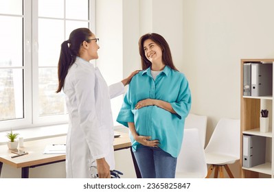 Happy young pregnant woman talking with her gynecologist doctor in hospital or medical clinic. Obstetrician doctor consulting female patient expecting a baby about pregnancy during check up. - Powered by Shutterstock